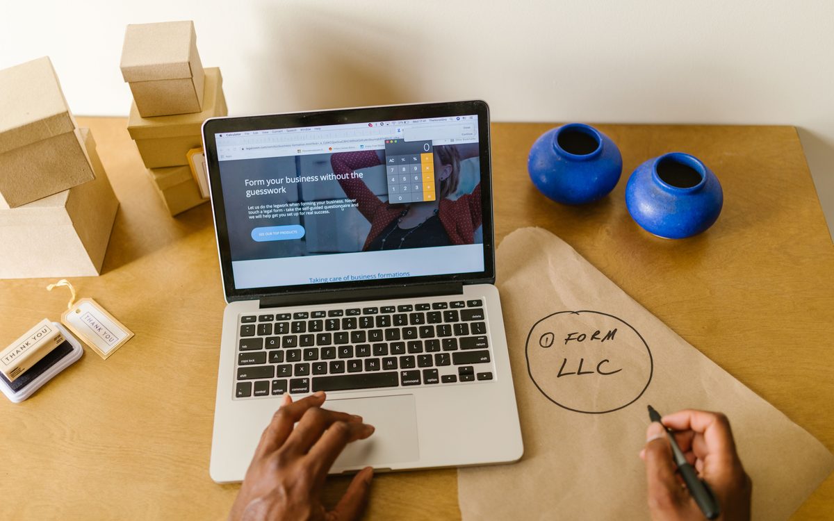 Laptop showing a website build alongside business planning notes
